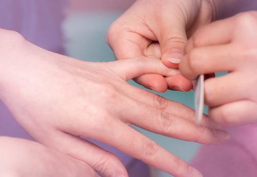 Woman receiving fingernail manicure service by professional  man