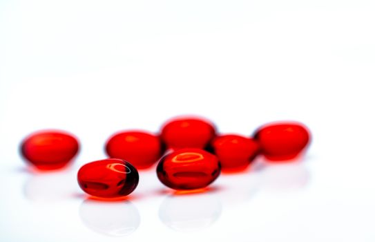 Red soft gel capsule pills isolated on white background. Pile of