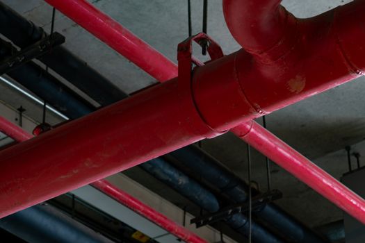 Fire sprinkler system with red pipes hanging from ceiling inside