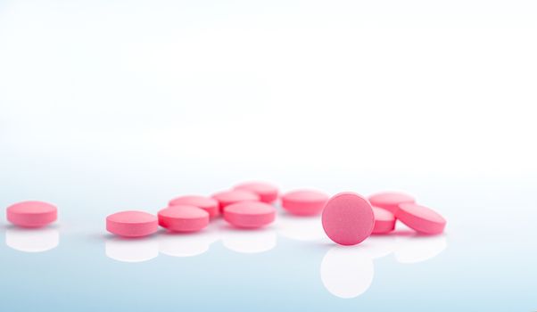 Round pink tablets pill on white background. Vitamins and minera