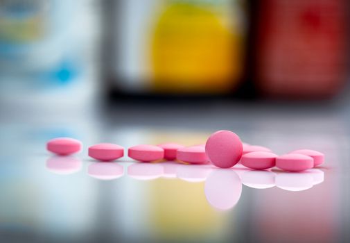 Pink tablets pills on blurred background of drug bottle in drugs