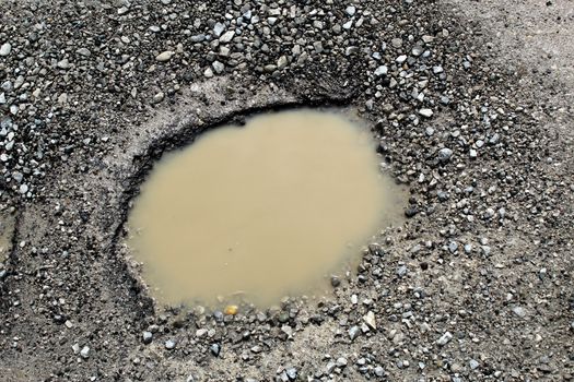 Pothole filled by water on a rural unpaved road