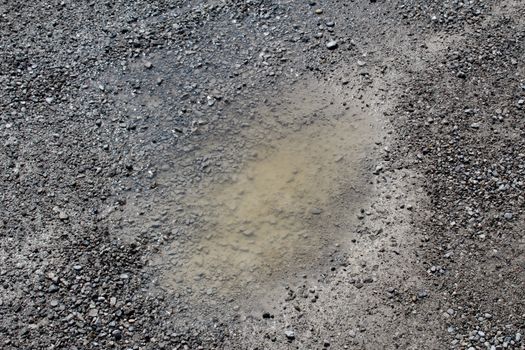 Small pothole full of water in a rural unpaved road