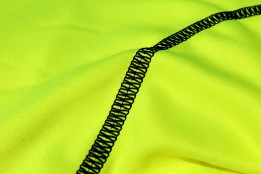Black seam on a light green textile with folds