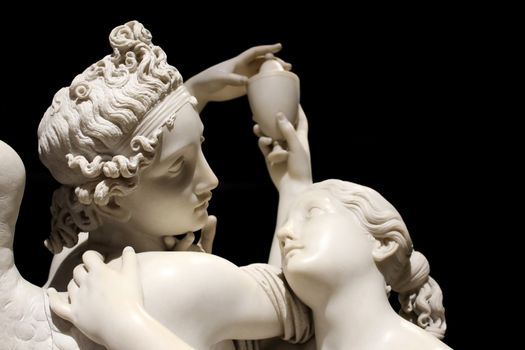 Cupid and Psyche myth white marble statue isolated on black background