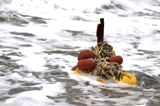 Iron stake with wound ropes and buoys in the breaking wave