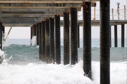 Under pier view. Waves beat about piles.