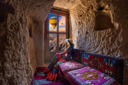 Woman sitting in cave house and looking to windows with beautiful scenic in Goreme, Cappadocia, Turkey.