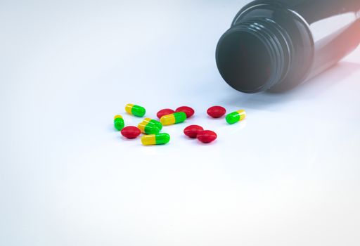 Red tablets and green-yellow capsule pills with amber plastic bo
