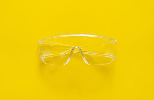 Protective glasses lying on a yellow background.