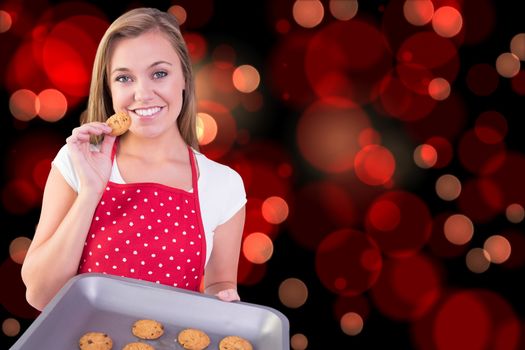 Composite image of pretty homemaker showing hot cookies