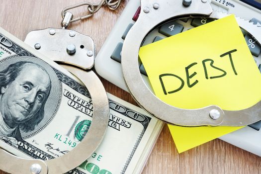 Debt in handcuffs and money for payment. Problems with loans.