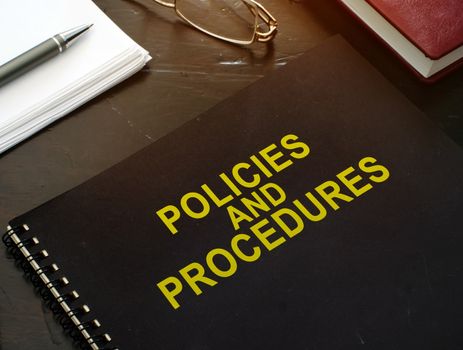 Policies and procedures company documents on a desk.