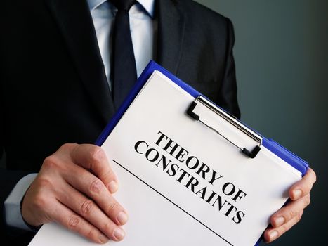 Businessman holds toc theory of constraints papers.
