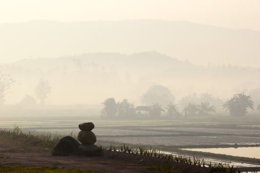 landscape of countryside in Thailand with mist in the early morning before sunrise with three rocks on the foreground. HDR.