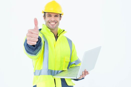 Architect in reflective clothing with laptop gesturing thumbs up