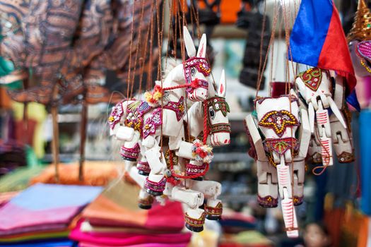 Sale of souvenirs in the market, Siem Reap, Cambodia. Funny handmade wooden puppets donkeys with bright colorful harness.