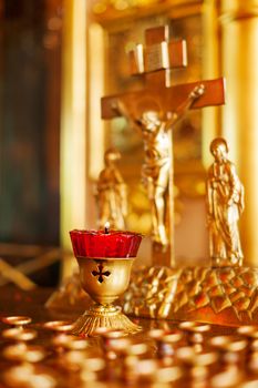 Golden candleholder in Orthodox church. Symbolic Orthodox gold cross with the crucifixion of Jesus.