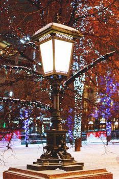 Old fashioned lantern on street. Trees are decorated for New Year and Christmas celebration. Moscow, Russia.