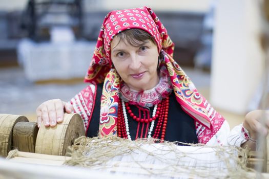 A Belarusian woman is weaving a towel. Take up weaving. Spin the towel.
