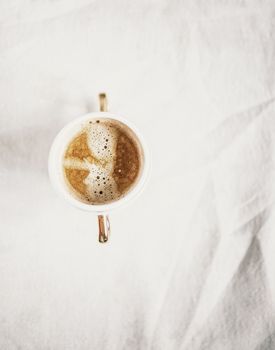 cup with cappuccino coffee on a light white retro sloppy fabric background. Copy space. Flat lay, top view. Minimalism