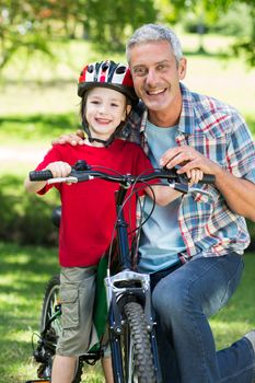 Happy little boy on his bike with his father 