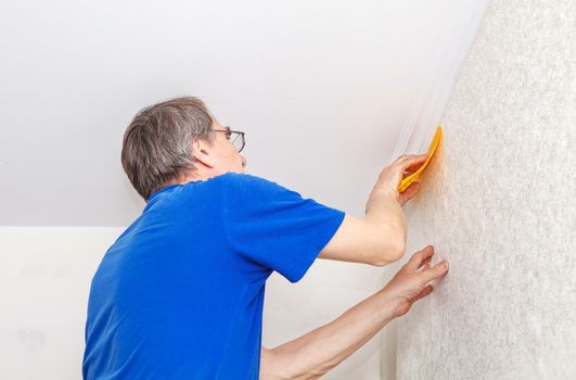 elderly worker smoothing wallpaper