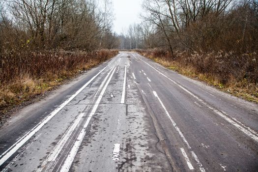 old abandoned asphalt road with spoiled road markings