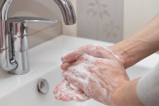 Man washing hands with soap and lathering suds. Protect against the coronavirus.