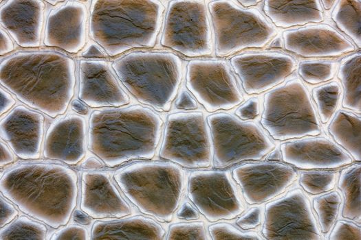 The texture of the concrete wall under the stylization of snake skin extruded from a large cobblestone, closeup.