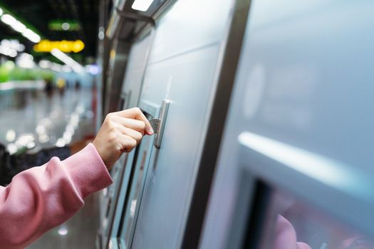 Woman hand inserts coin to buy subway train ticket in machine. T