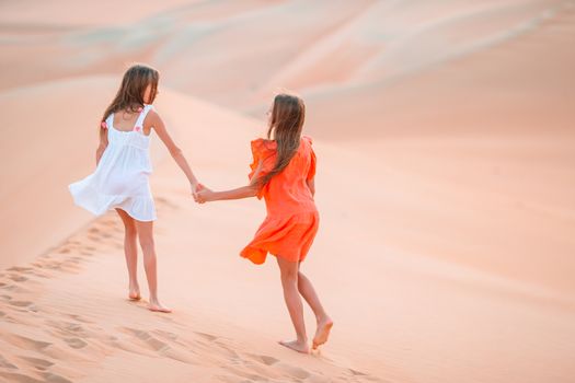 Girls among dunes in big desert in Emirates