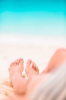 Woman's feet on the white sand beach in shallow water