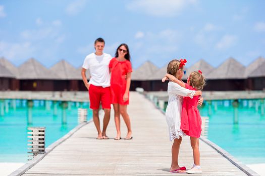 Young family in red on wooden jetty in Maldives