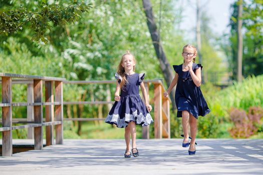 Adorable little school girls outdoors in warm september day. Back to school.