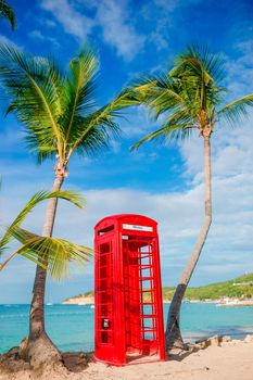 Red phone booth in Dickenson's bay Antigua. Beautiful landscape with a classic phone booth on the white sandy beach in Antigua