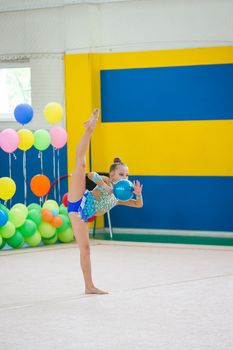 Beautiful little gymnast girl with her performance with ball on the carpet