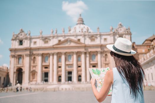 Happy young woman with city map in Vatican city and St. Peter's Basilica church, Rome, Italy.