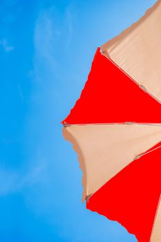 Closeup of a red andd yellow sun umbrella on background of blue sky