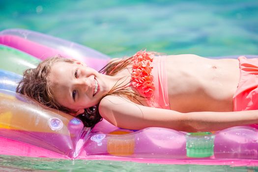 Adorable girl on inflatable air mattress in the sea