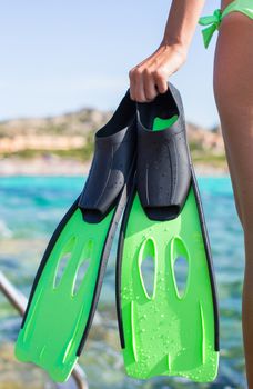 Diving goggles, snorkel and snorkeling fins at woman hands