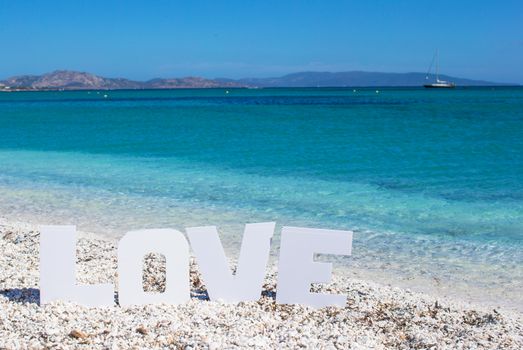 Word love on tropical beach background of the turquoise sea and blue sky