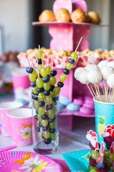 Canape of fruit, white chocolate cake pops and popcorn on sweet children's table at birthday party
