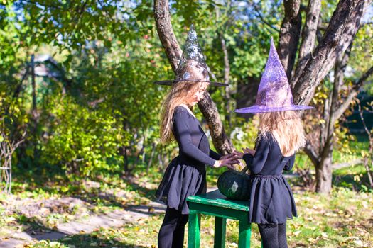 Little girls casting a spell on Halloween in witch costume