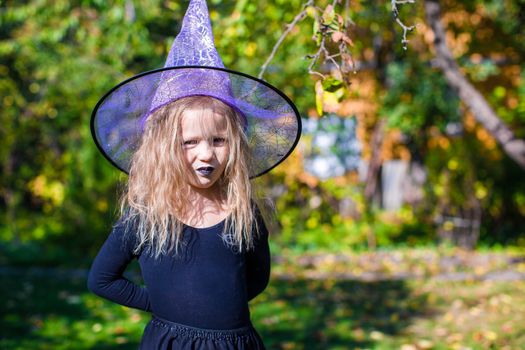 Adorable little girl in witch costume casts a spell on Halloween