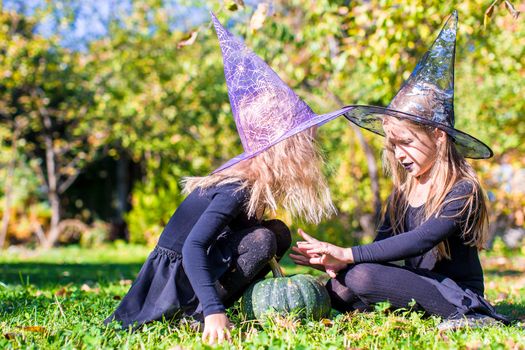 Adorable little girls in witch costume casting a spell on Halloween