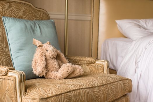Soft plush toy bunny on a chair in a hotel room
