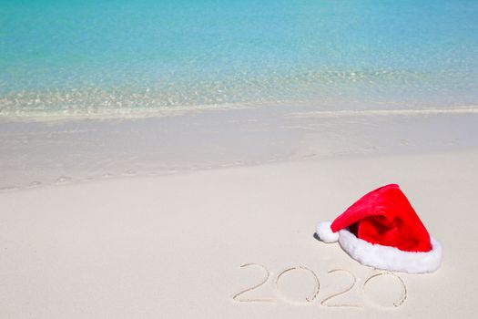 2016 written on tropical beach white sand with xmas hat