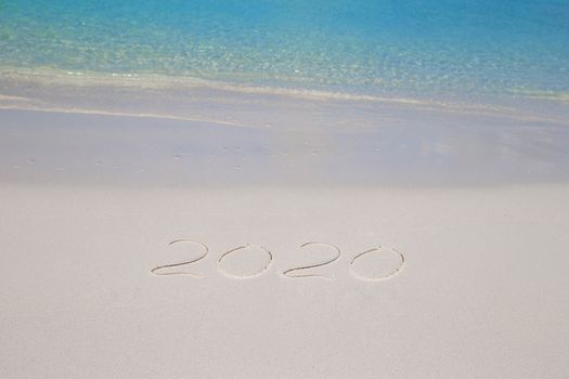 2016 written on tropical beach white sand with xmas hat