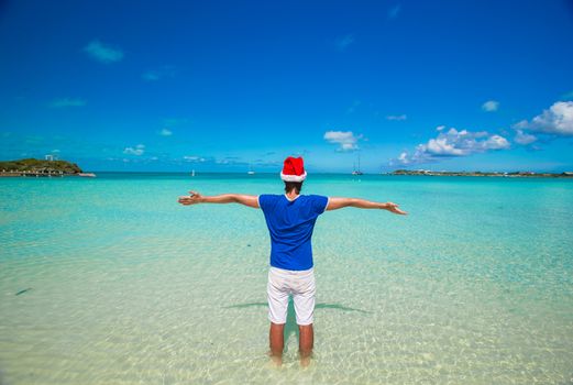 Young man in santa hat on tropical beach